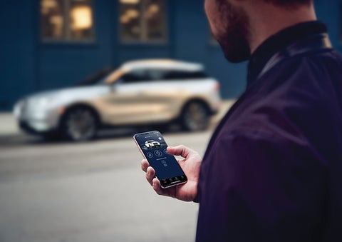 A person is shown interacting with a smartphone to connect to a Lincoln vehicle across the street. | Courtesy Lincoln in Altoona PA