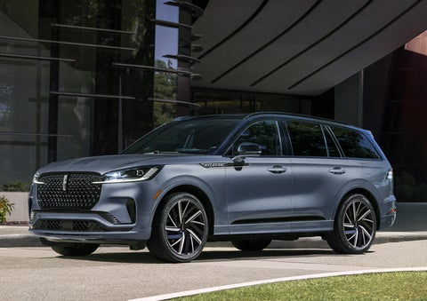 A gray 2025 Lincoln Aviator® SUV is parked outside a modern building showcasing the driver’s side of the vehicle. | Courtesy Lincoln in Altoona PA