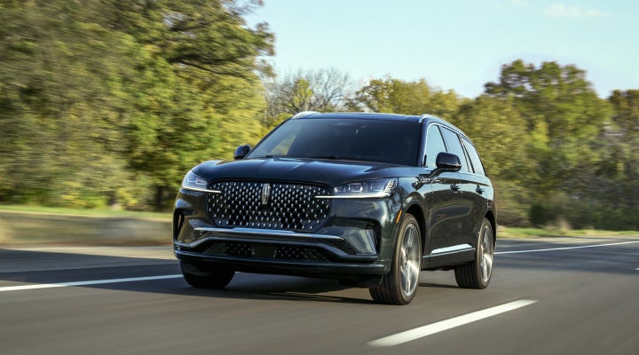 A 2026 Lincoln Black Label™ Aviator® SUV is being driven down a road lined with trees. | Courtesy Lincoln in Altoona PA
