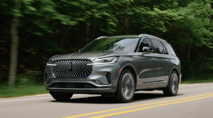 A 2027 Lincoln Aviator® SUV is being driven down a road lined with trees. | Courtesy Lincoln in Altoona PA